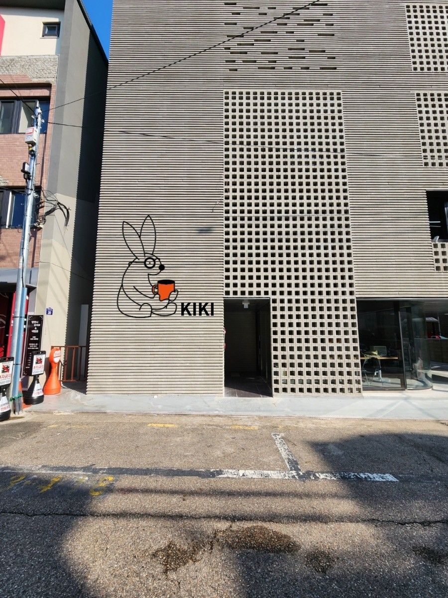 회색 벽돌 외벽에 검은 선으로 그린 토끼 로고와 KIKI 글자